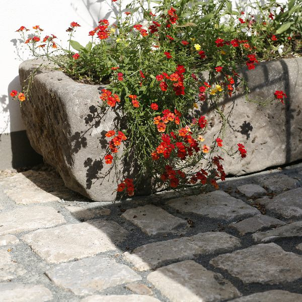 Gartengestaltung mit Natursteinpflaster und Pflanzgefäß im Garten- und Landschaftsbau