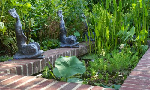 Ziergarten mit Wasserbecken, Ziegelrand und dekorativen Wasserspeiern